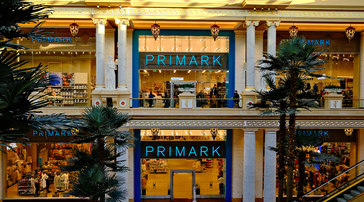 Devanture sur deux étages de la boutique Primark avec une enseigne bleu,des escalators et des palmiers en premier plan